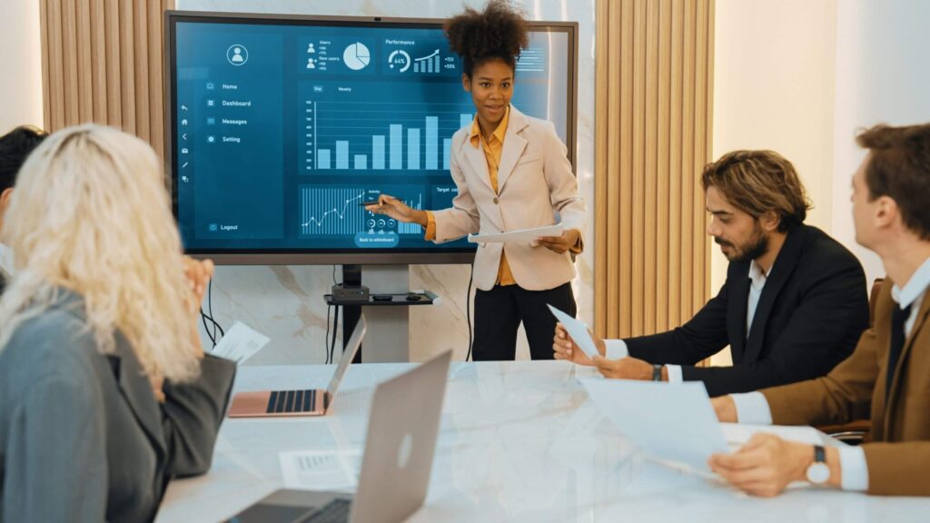 A team discussing data on a large screen with clear graphs and KPIs